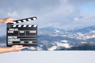 Assistant holding clapperboard outdoors, closeup. Cinema production 