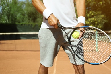 Sportsman playing tennis at court on sunny day, closeup