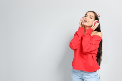 Photo of Young woman listening to Christmas music on color background