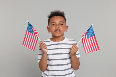 Photo of 4th of July - Independence Day of USA. Happy boy with American flags on light grey background