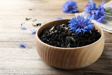 Photo of Dried cornflower tea and fresh flowers on wooden table