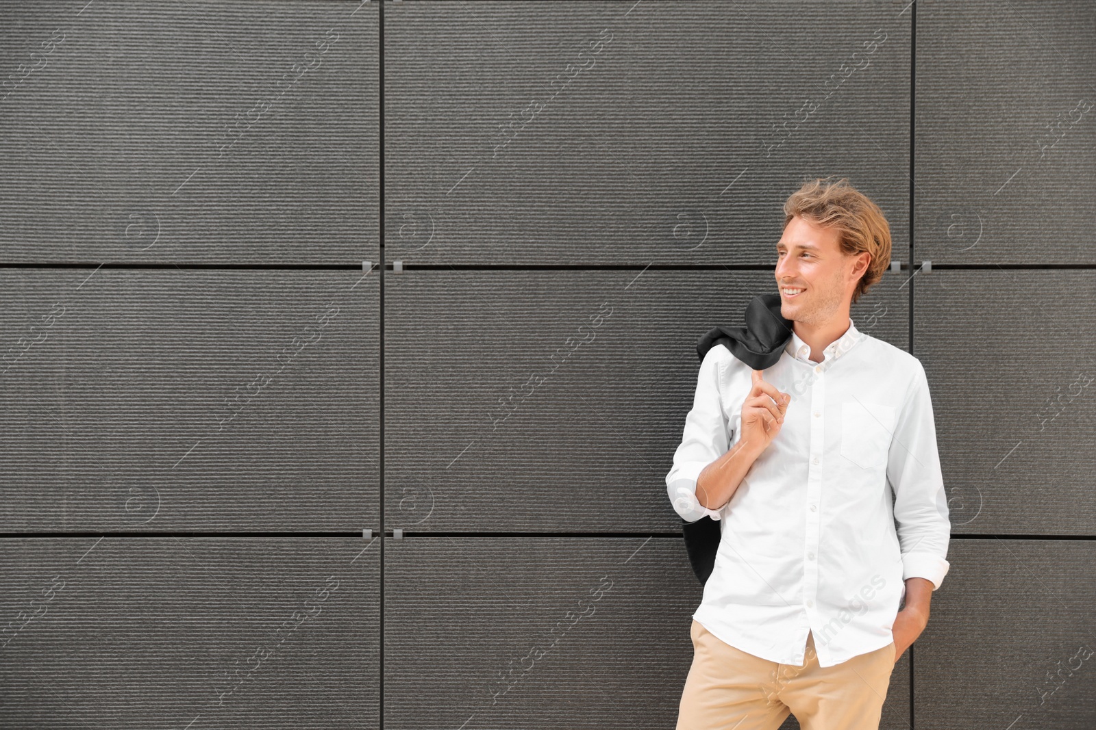 Photo of Portrait of handsome young man leaning to wall outdoors, space for text