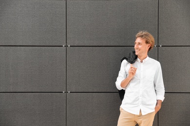 Photo of Portrait of handsome young man leaning to wall outdoors, space for text