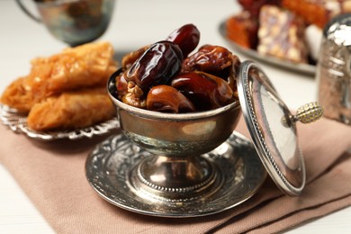 Date fruits, Turkish delight and baklava dessert served in vintage tea set on white wooden table, closeup