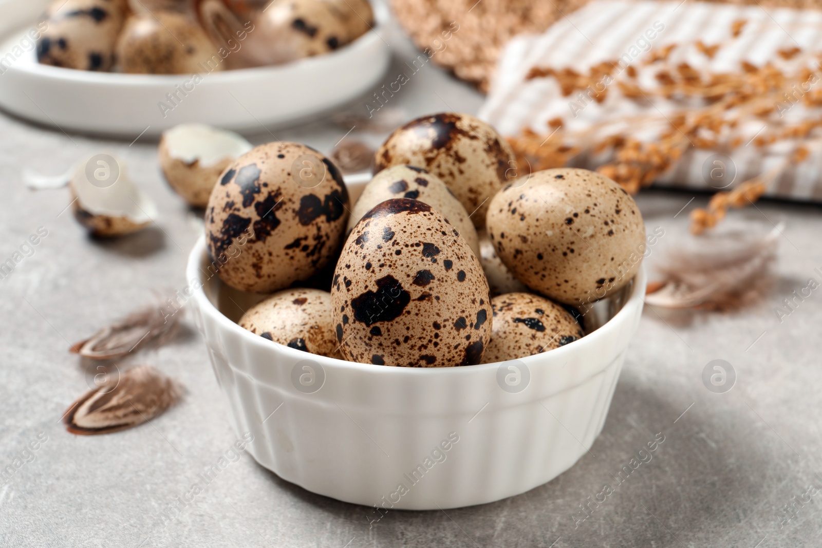 Photo of Fresh quail eggs in bowl on light grey table