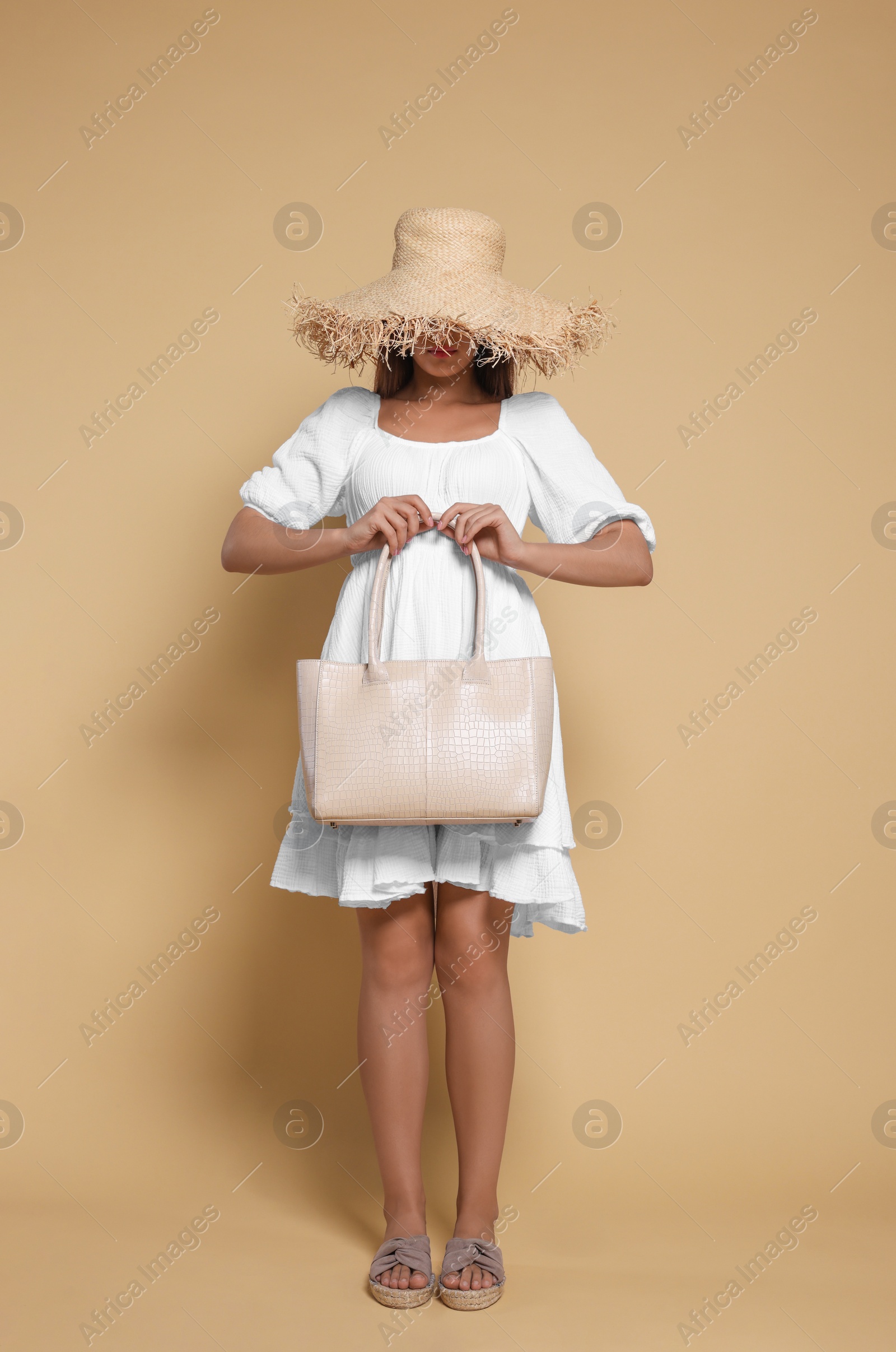 Photo of Young woman with stylish bag on beige background