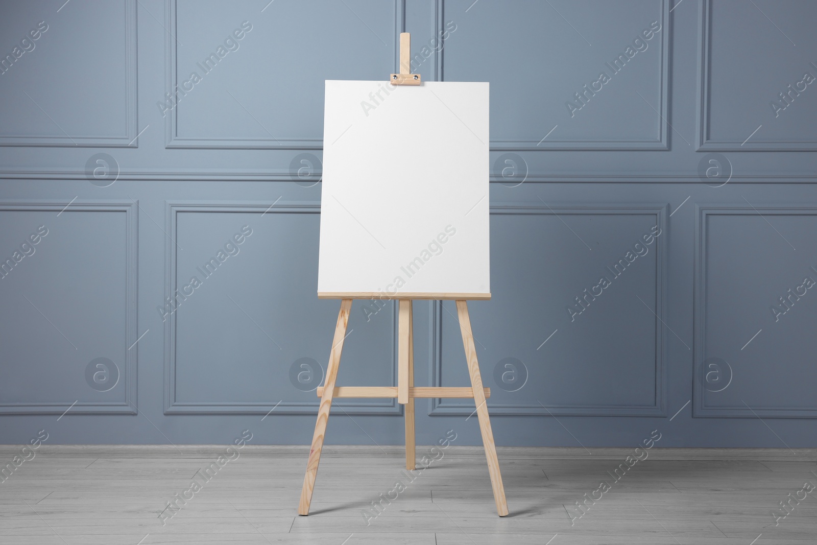 Photo of Wooden easel with blank canvas near grey wall indoors