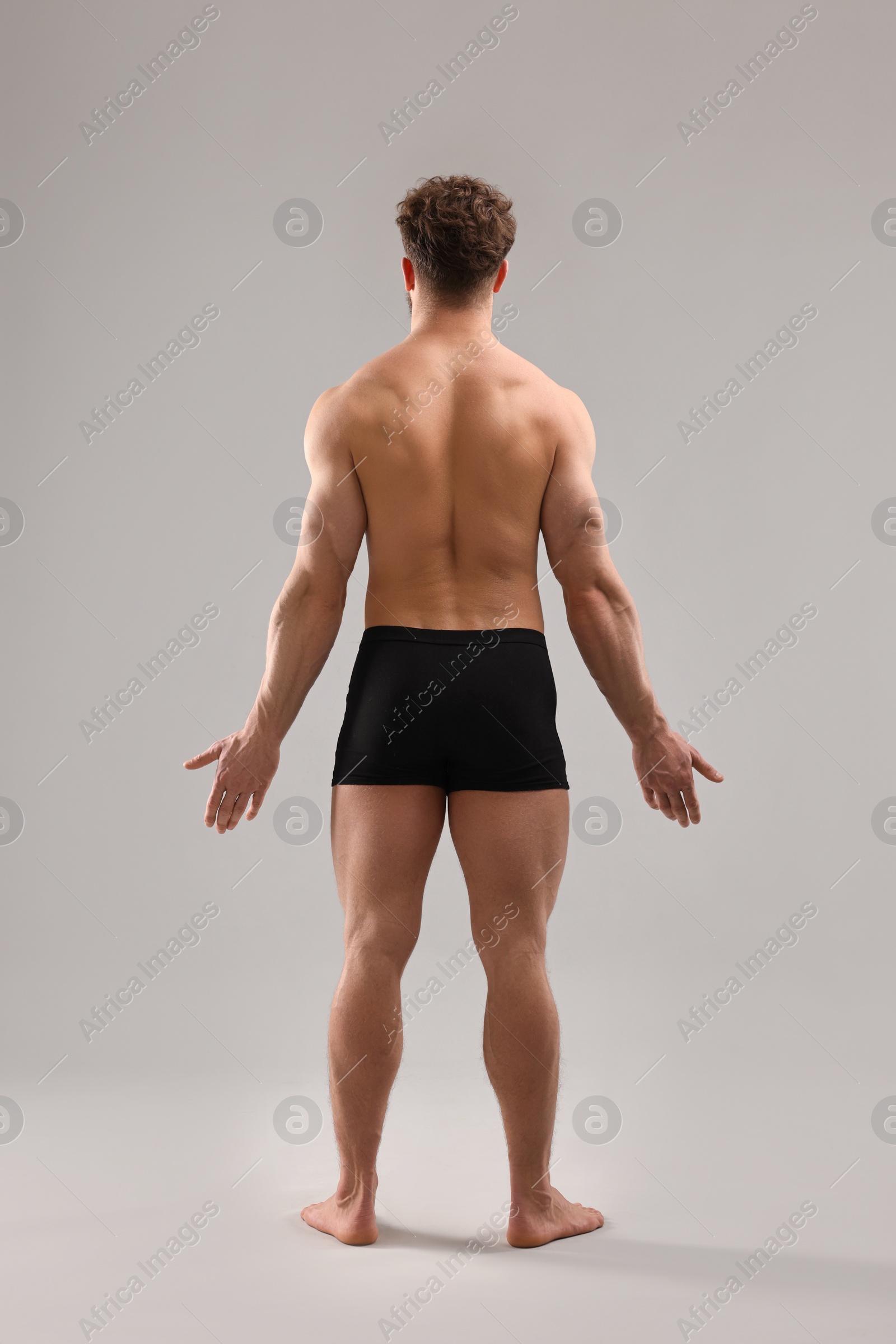 Photo of Man with muscular body on light grey background, back view