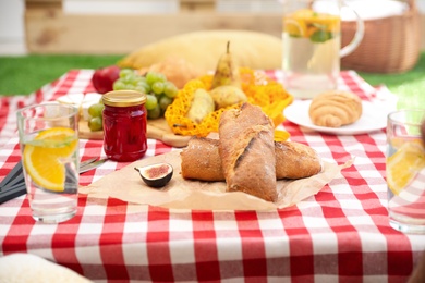 Photo of Different tasty food on picnic blanket, closeup