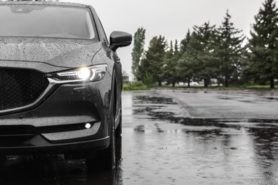 Photo of Modern car parked outdoors on rainy day