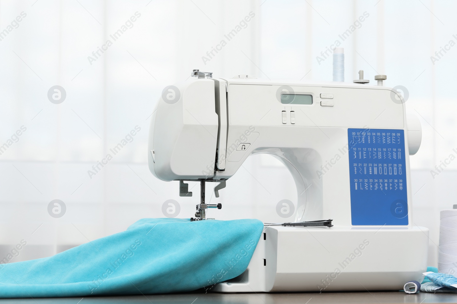 Photo of Sewing machine with fabric and craft accessories on wooden table indoors