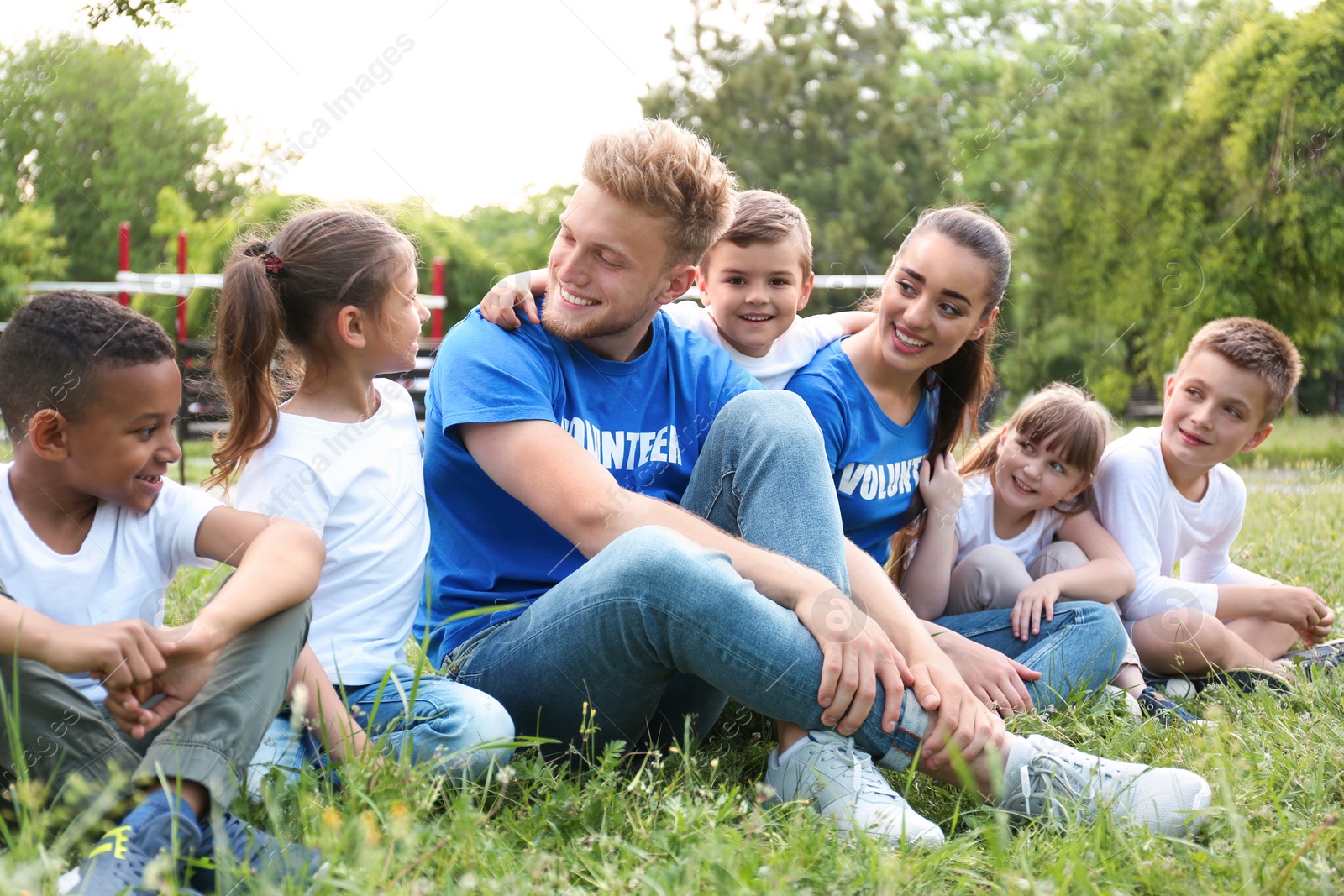 Photo of Volunteers and kids sitting on grass in park