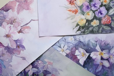 Photo of Paper sheets with beautiful floral watercolor paintings, closeup