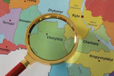 Golden magnifying glass above Vinnytsia region on map of Ukraine, closeup