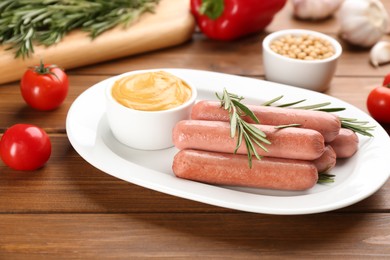 Photo of Delicious vegetarian sausages with rosemary and sauce on wooden table