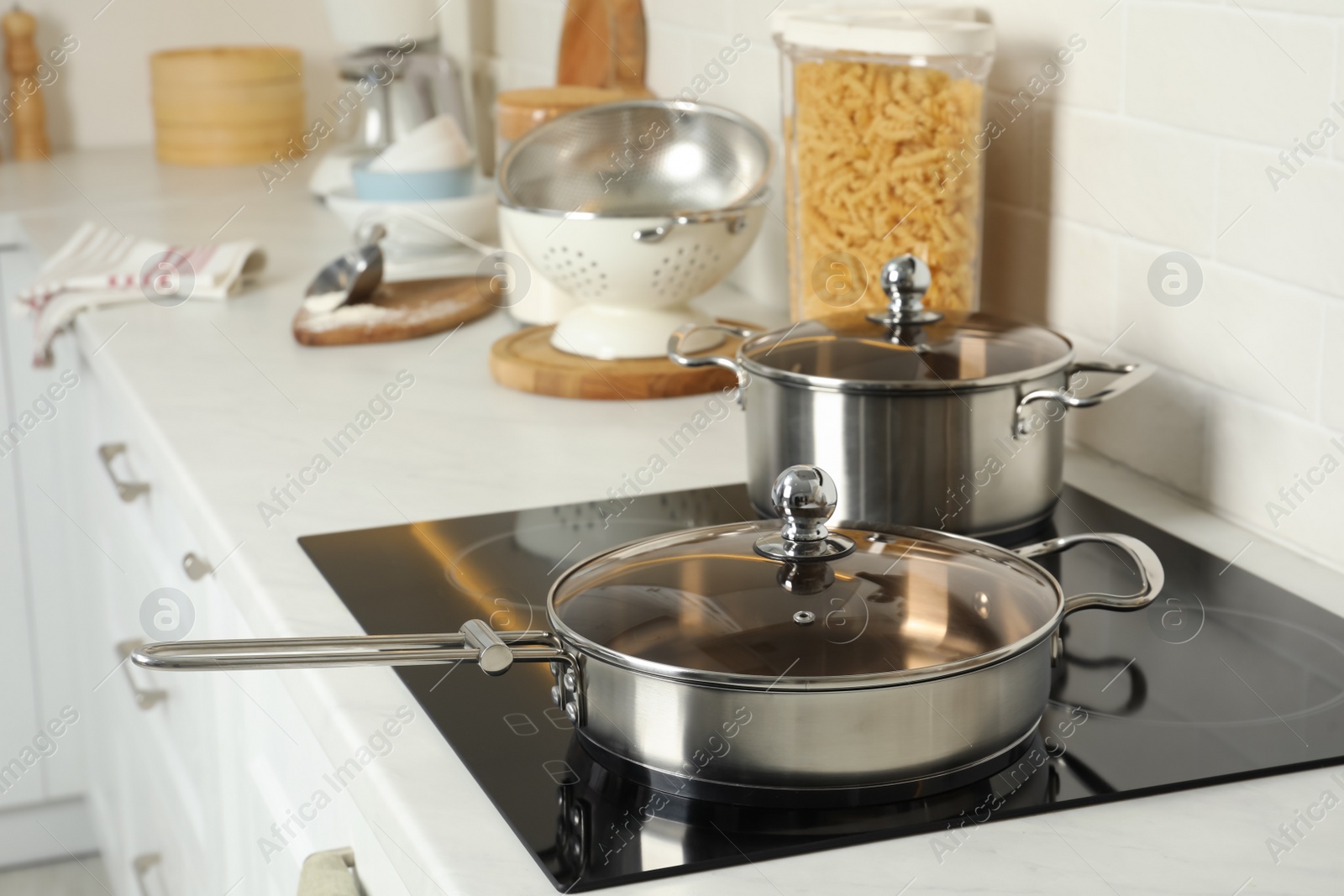 Photo of Pot and pan on electric stove in kitchen. Cooking utensils