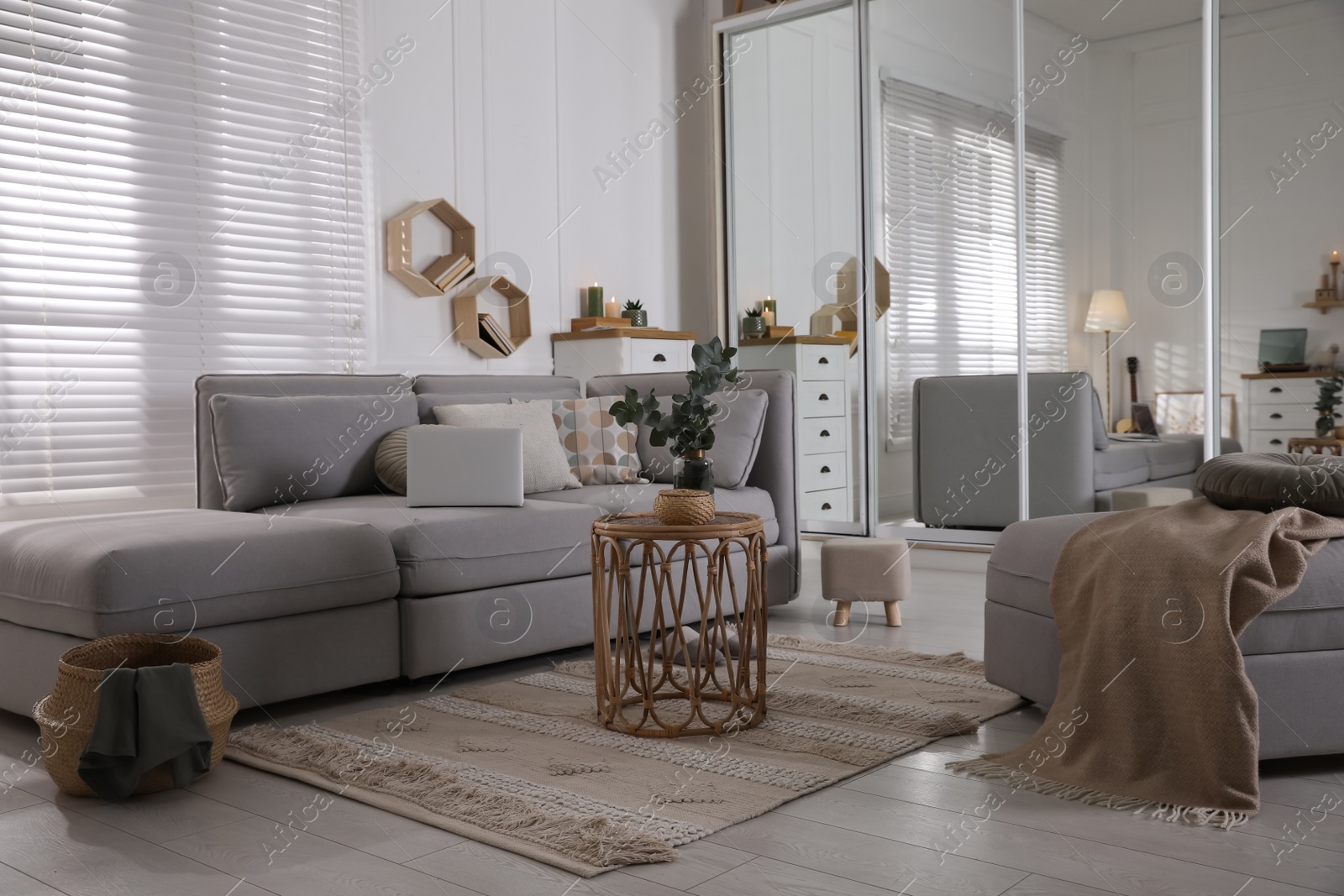 Photo of Comfortable grey sofa, ottoman and wardrobe with mirror doors in living room interior