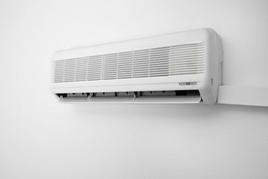 Photo of Modern air conditioner on white wall indoors