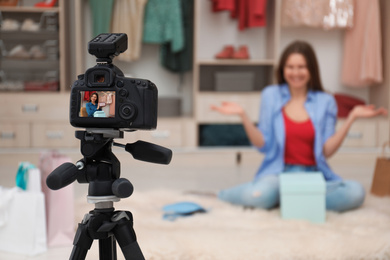 Photo of Fashion blogger recording new video in room, focus on camera