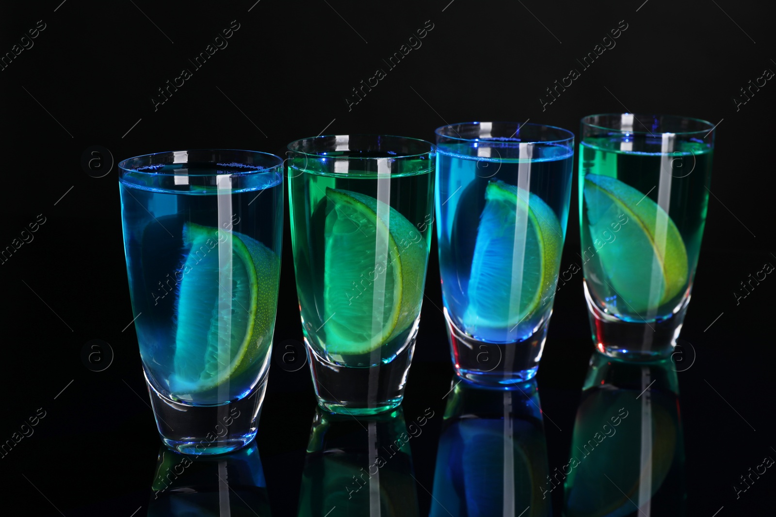 Photo of Alcohol drink with citrus wedges in shot glasses on mirror surface