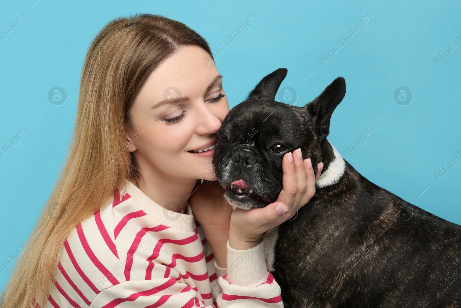 Photo of Portrait of happy woman with cute French Bulldog on light blue background