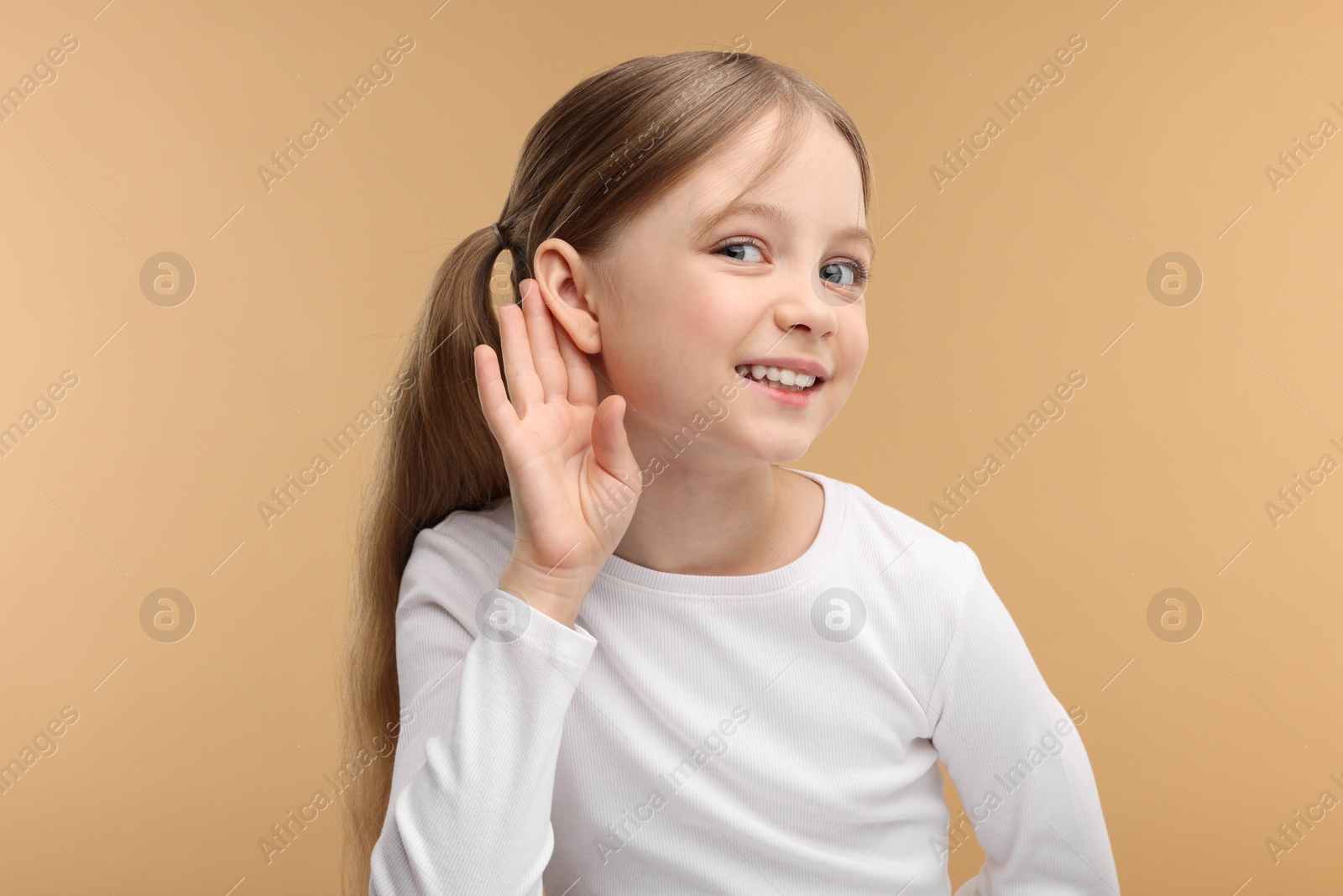 Photo of Little girl with hearing problem on pale brown background