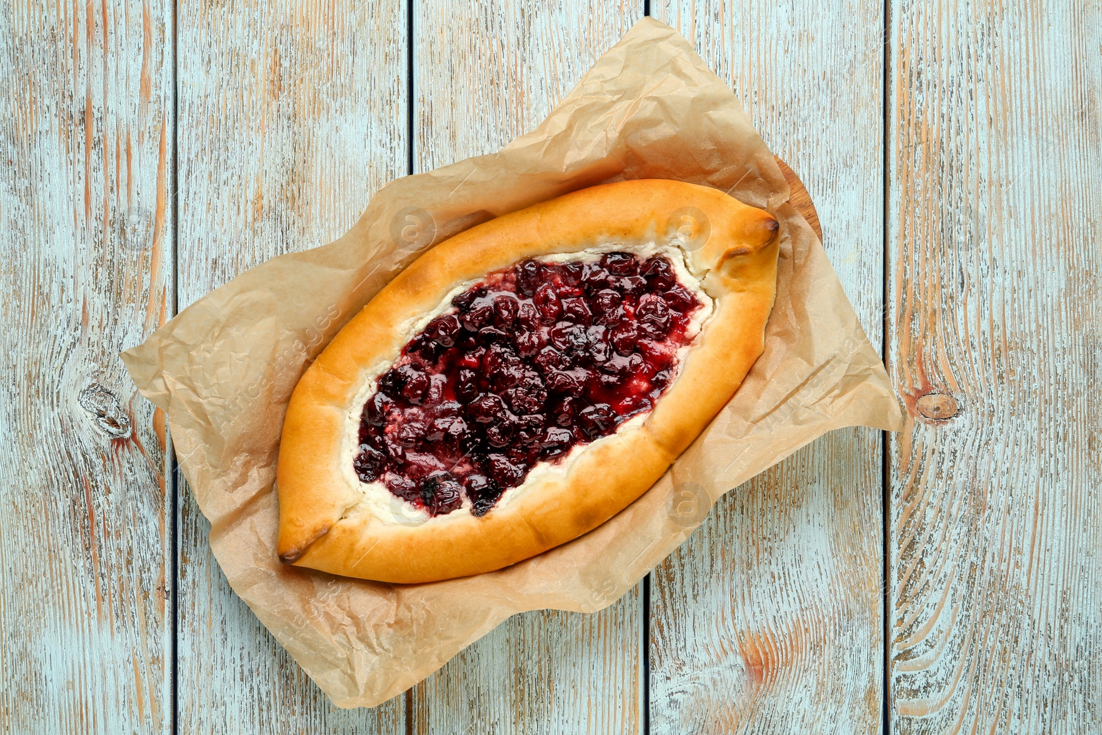 Photo of Delicious sweet cottage cheese pastry with cherry jam on light blue wooden table, top view