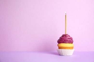 Photo of Birthday cupcake with candle on violet background, space for text