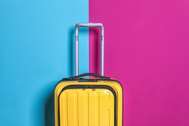 Packed bright yellow suitcase on color background