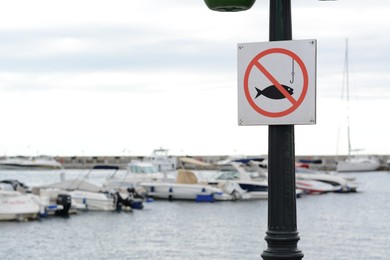Photo of Post with No fishing sign near sea. Space for text