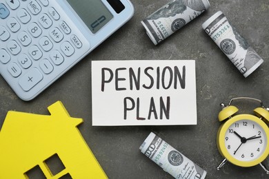 Photo of Card with words Pension Plan, calculator, house figure, alarm clock and dollar banknotes on grey table, flat lay