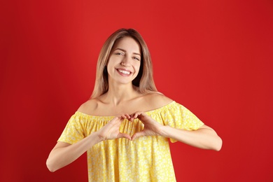 Photo of Portrait of pretty woman making heart with her hands on color background