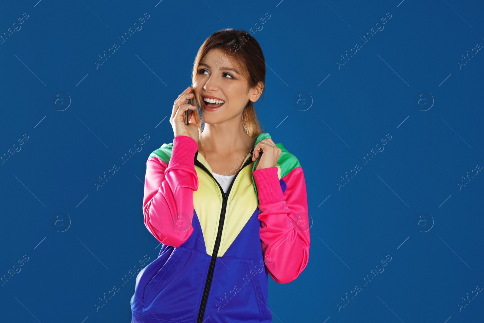 Photo of Young woman talking on smartphone against blue background