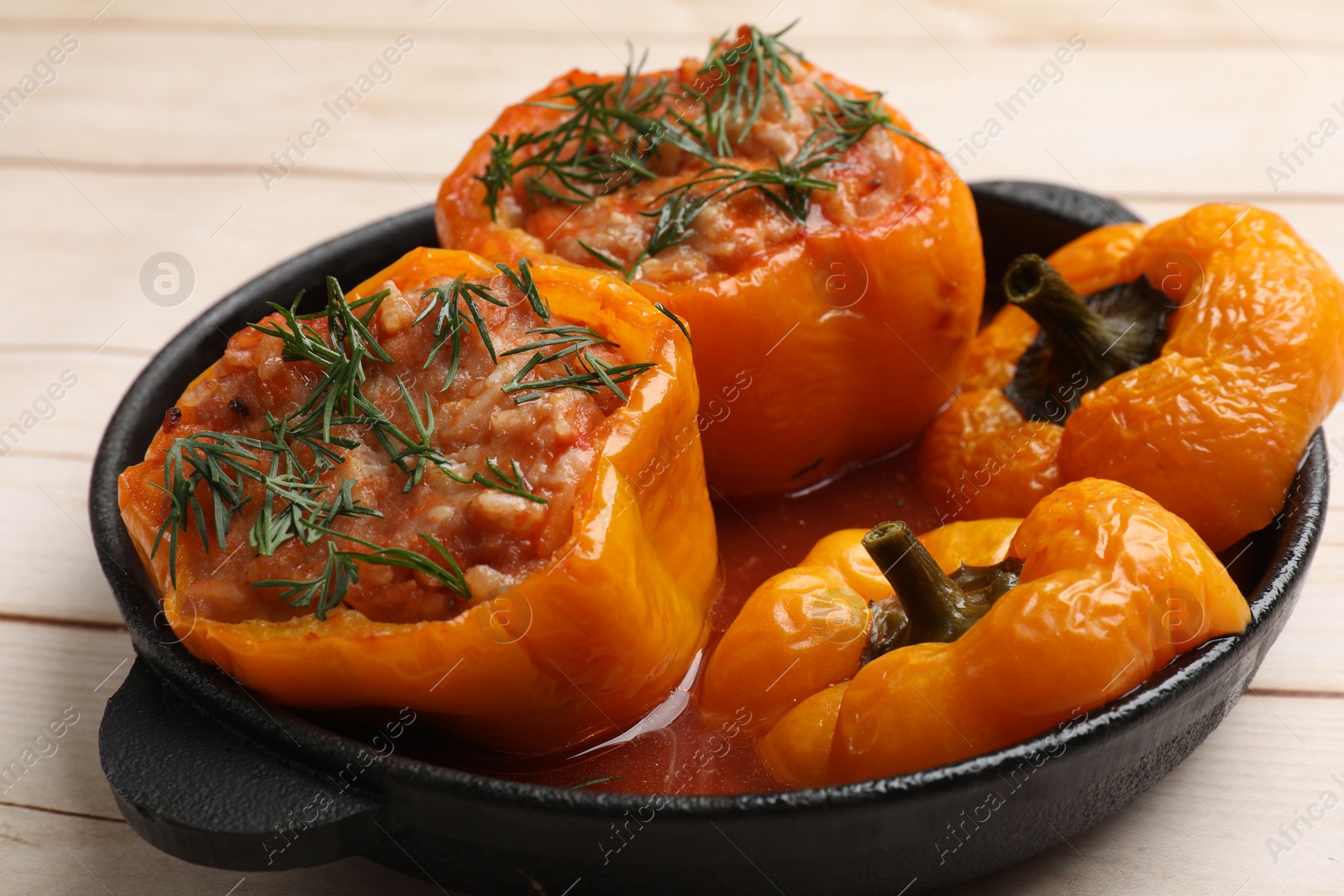 Photo of Tasty stuffed peppers in pan on light wooden table, closeup