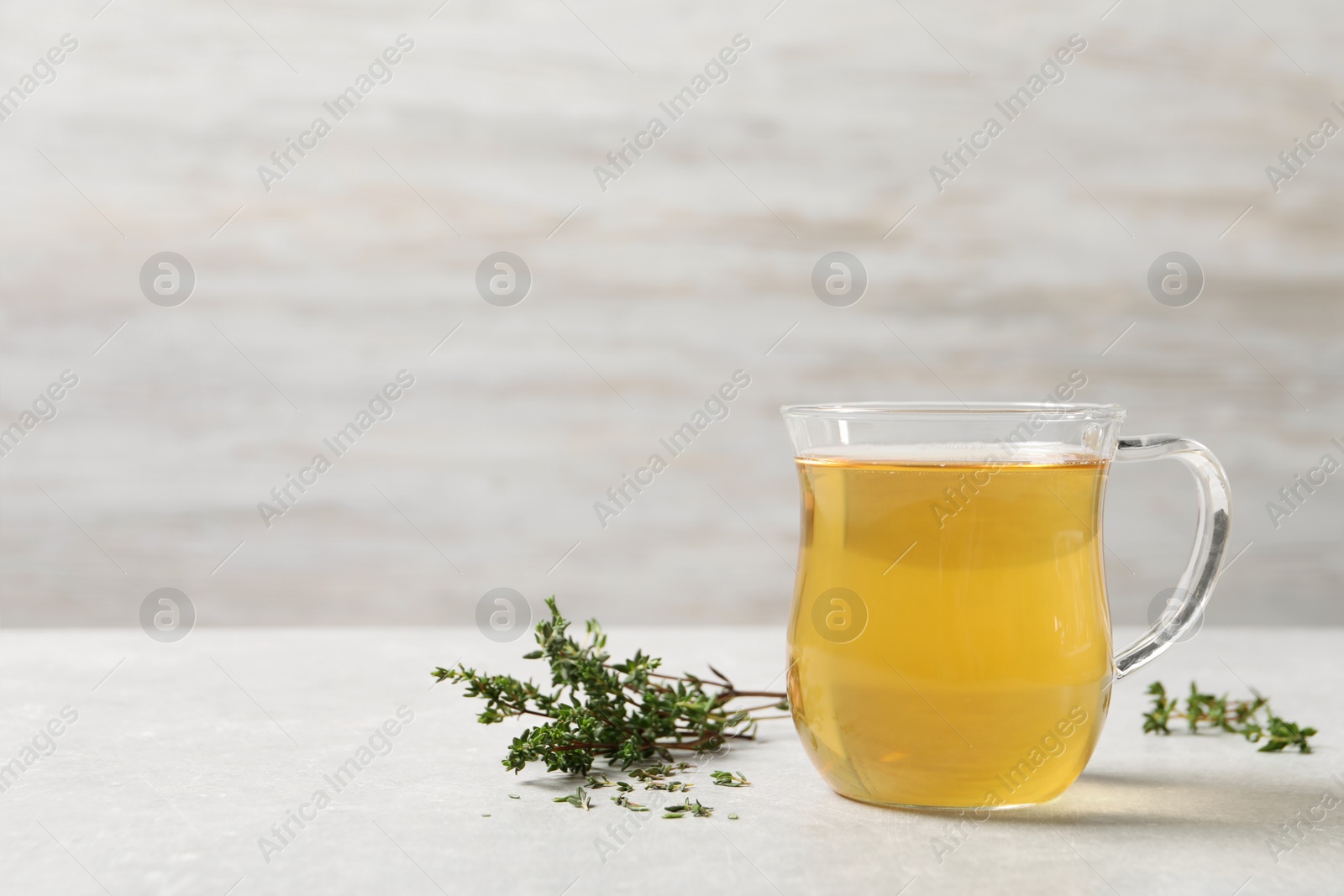 Photo of Aromatic herbal tea with thyme on light table, space for text