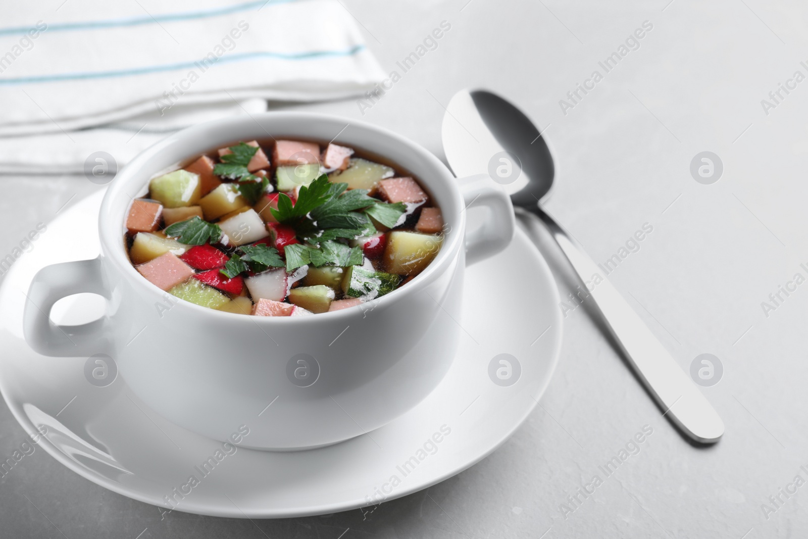 Photo of Delicious cold okroshka with kvass served on light grey table. Traditional Russian summer soup