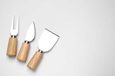 Cheese knives and fork on white background, top view