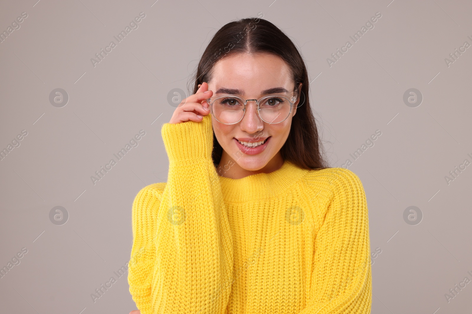 Photo of Beautiful young woman in stylish warm sweater on grey background