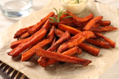 Photo of Board with delicious sweet potato fries and sauce on table, closeup