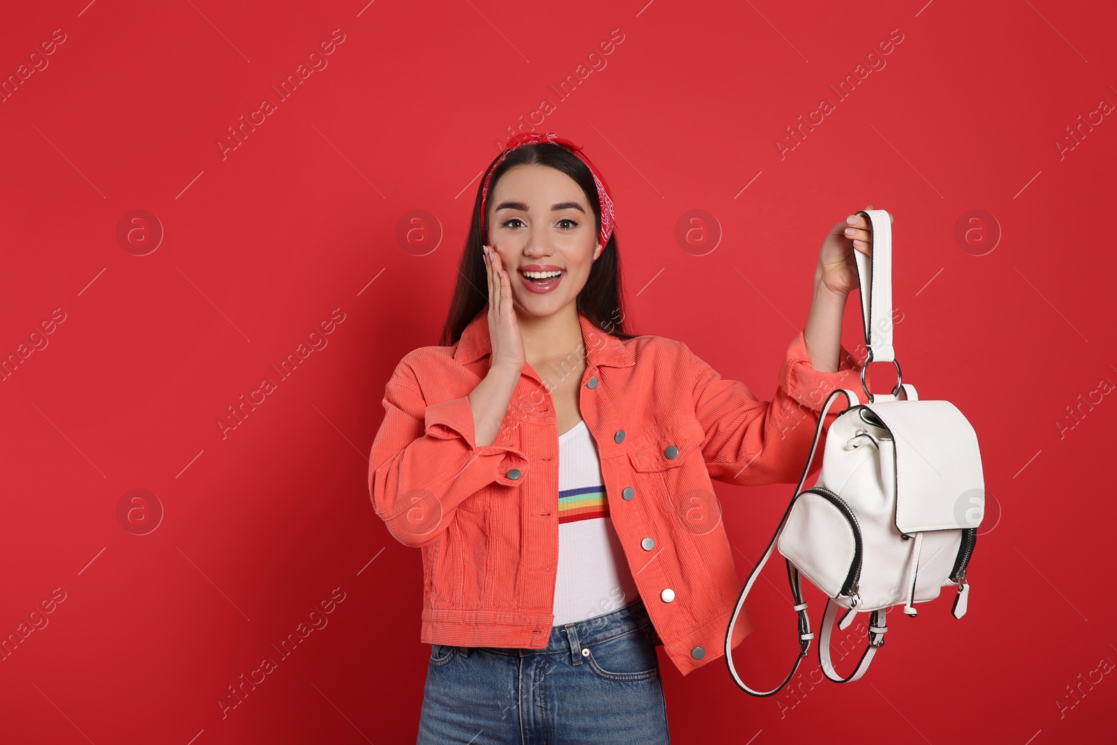 Photo of Beautiful young woman with stylish leather backpack on red background