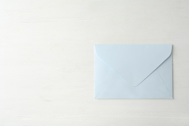 Photo of Light paper envelope on white wooden table, top view. Space for text