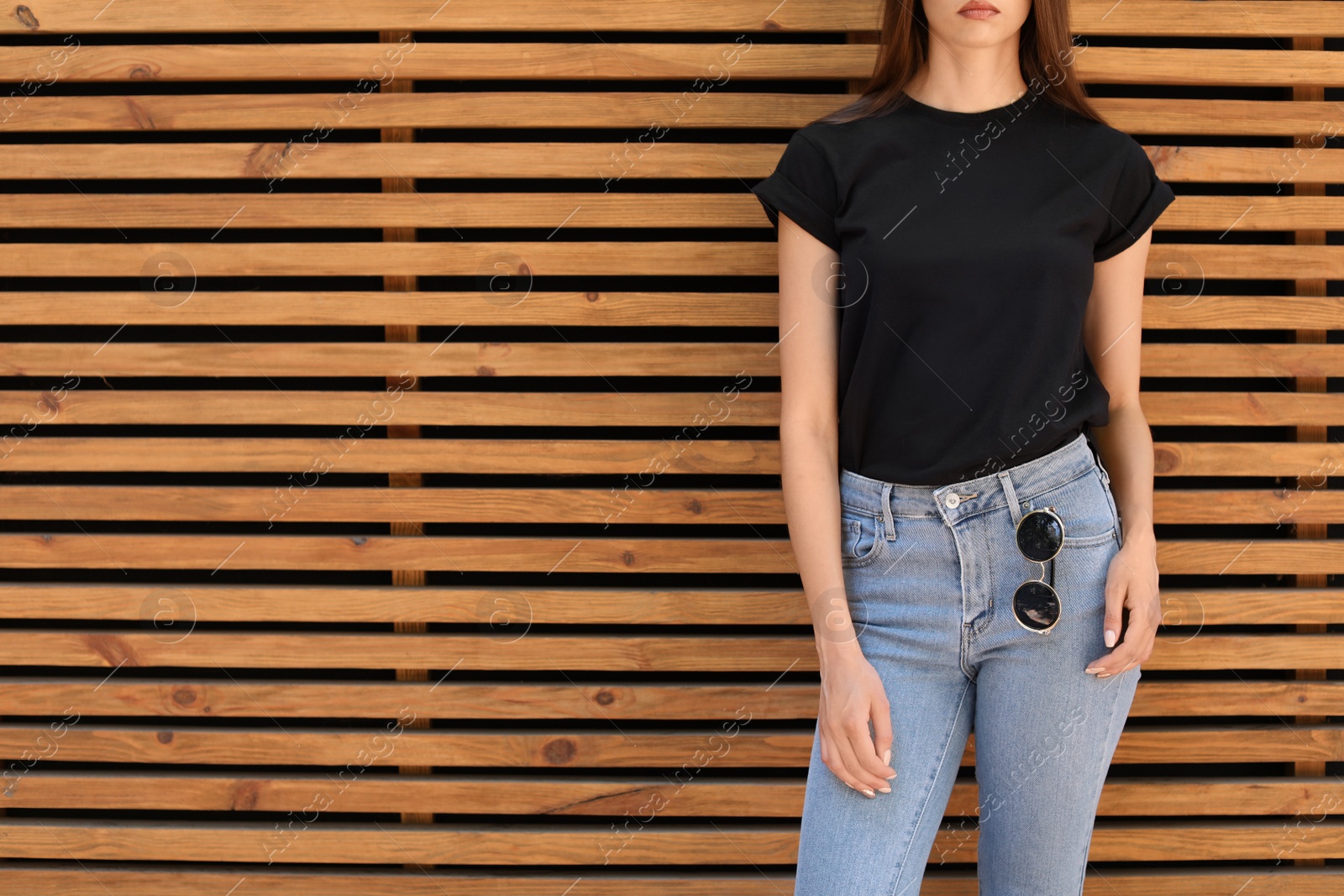 Photo of Young woman wearing black t-shirt against wooden wall on street. Urban style