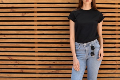 Young woman wearing black t-shirt against wooden wall on street. Urban style