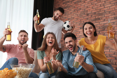 Group of friends watching football at home