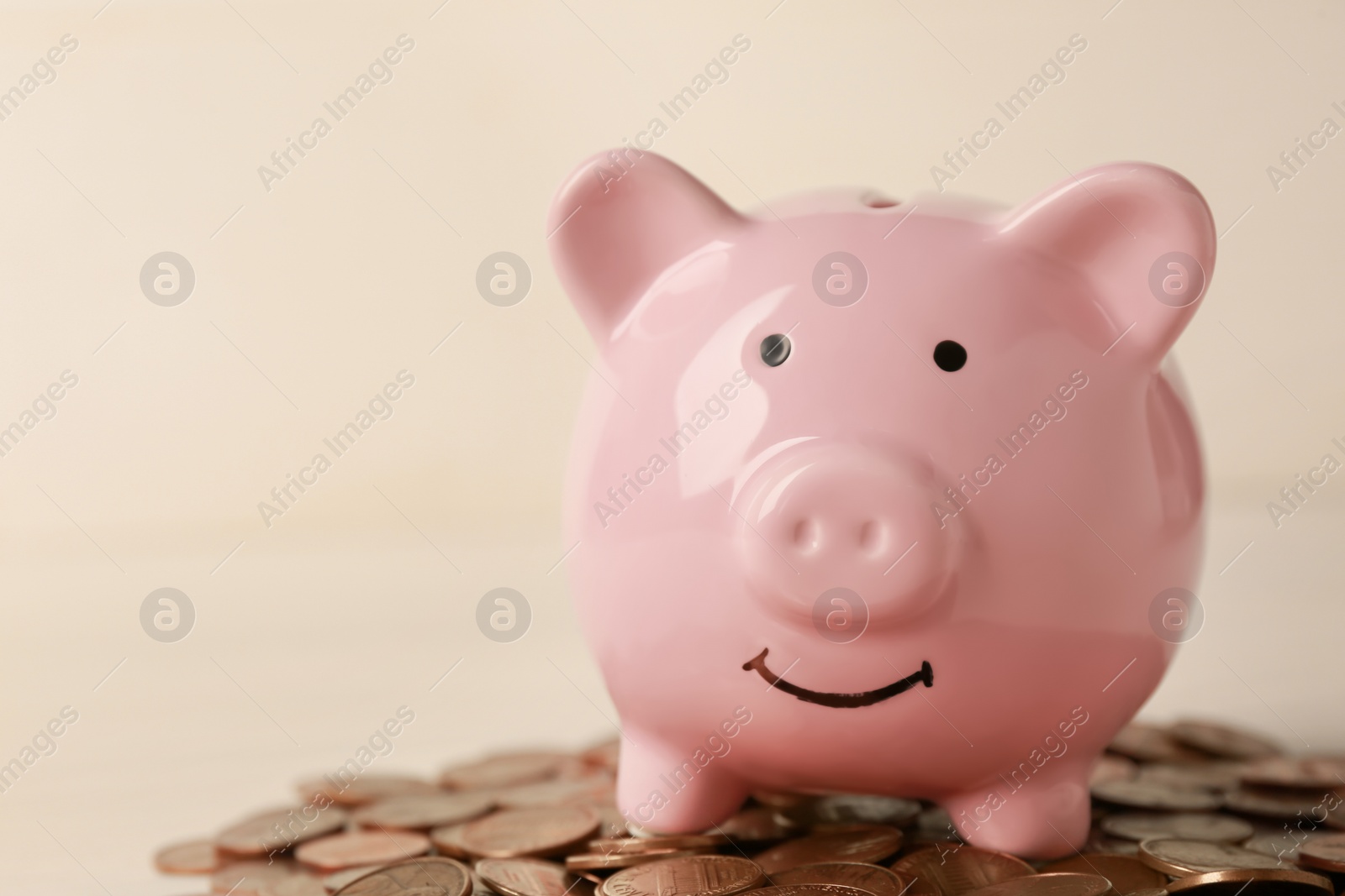 Photo of Ceramic piggy bank and coins on white wooden table, closeup. Space for text