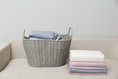 Laundry basket with clean clothes on sofa indoors