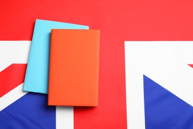 Photo of Learning foreign language. Different books on flag of United Kingdom, top view with space for text