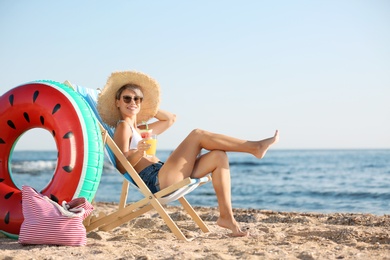 Photo of Young woman with cocktail in beach chair at seacoast