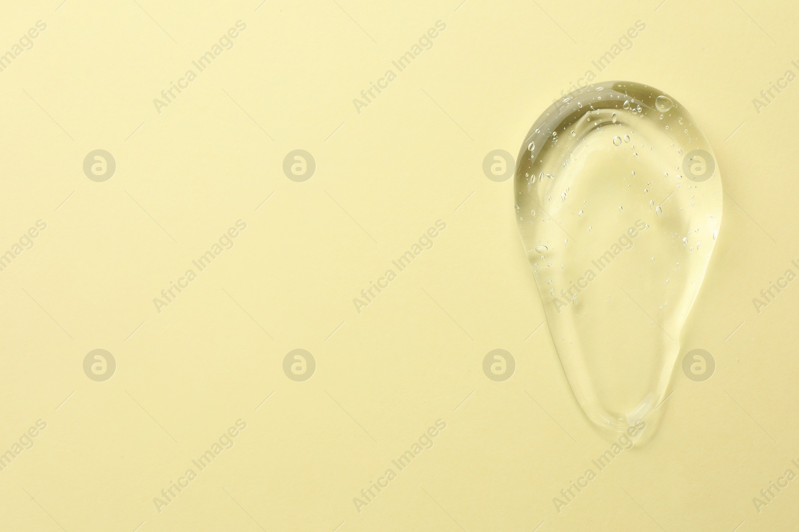 Photo of Clear cosmetic gel on yellow background, top view. Space for text