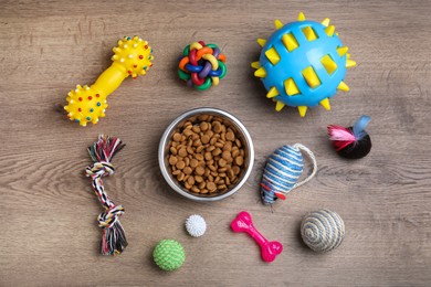 Flat lay composition with different pet toys and feeding bowl on wooden background